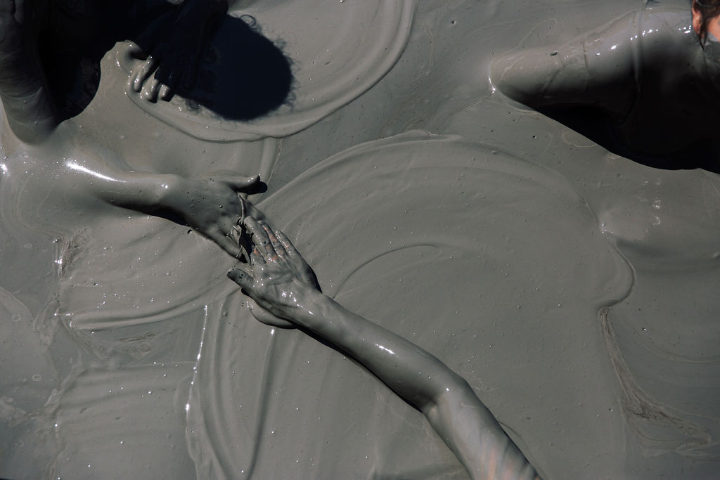 Two hands reaching through clay